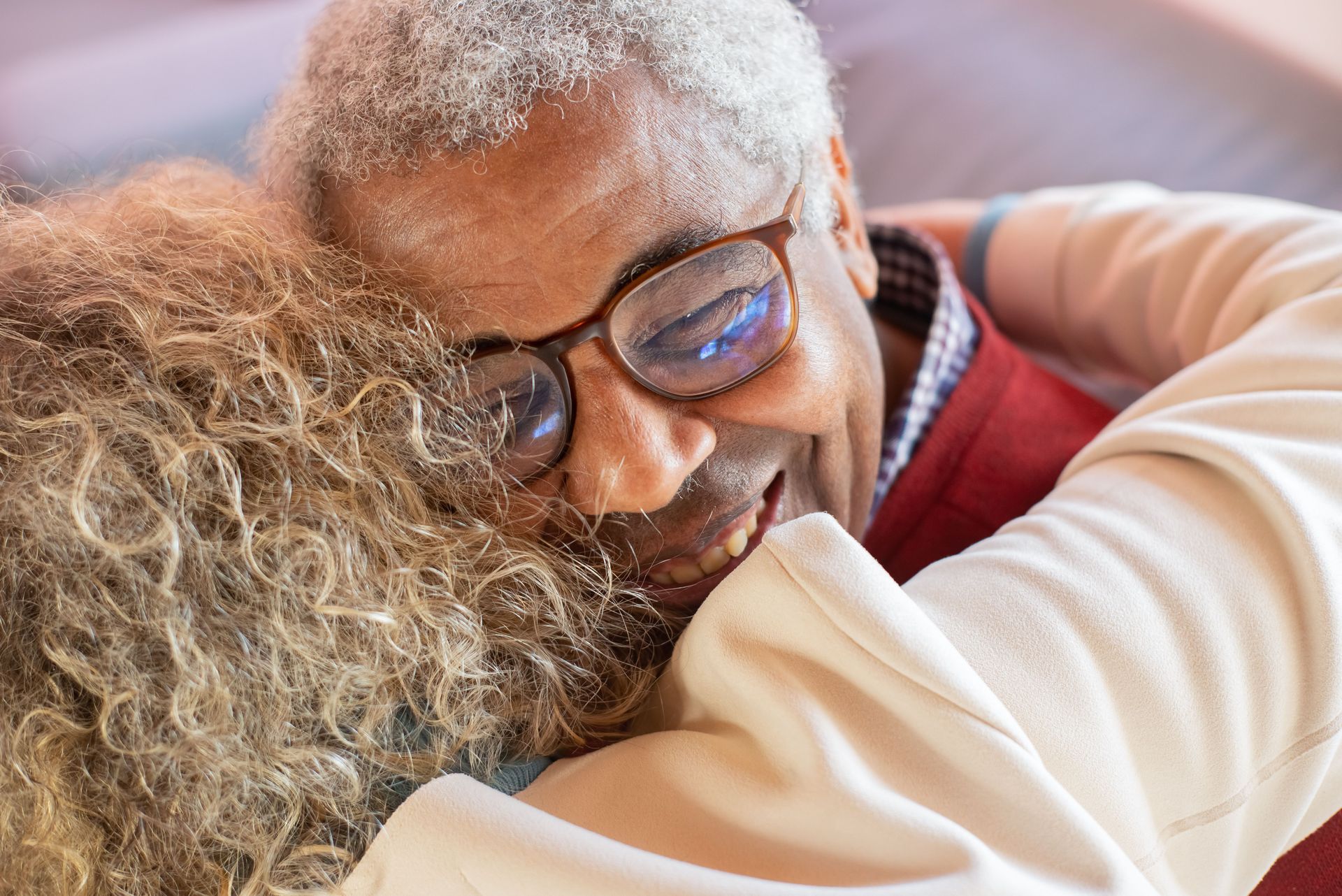 Two people embracing closely, one wearing glasses and smiling