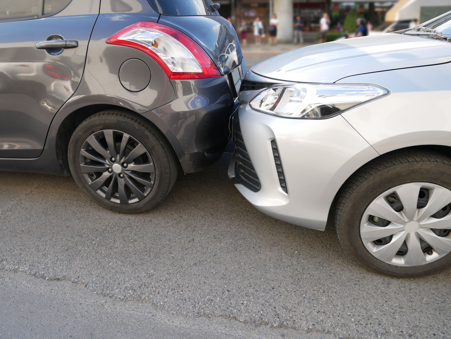 Two cars in a minor rear-end collision on a street, black SUV backed into a white car.