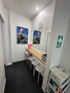 Hair station with a mirror, artwork, stools, and first aid 