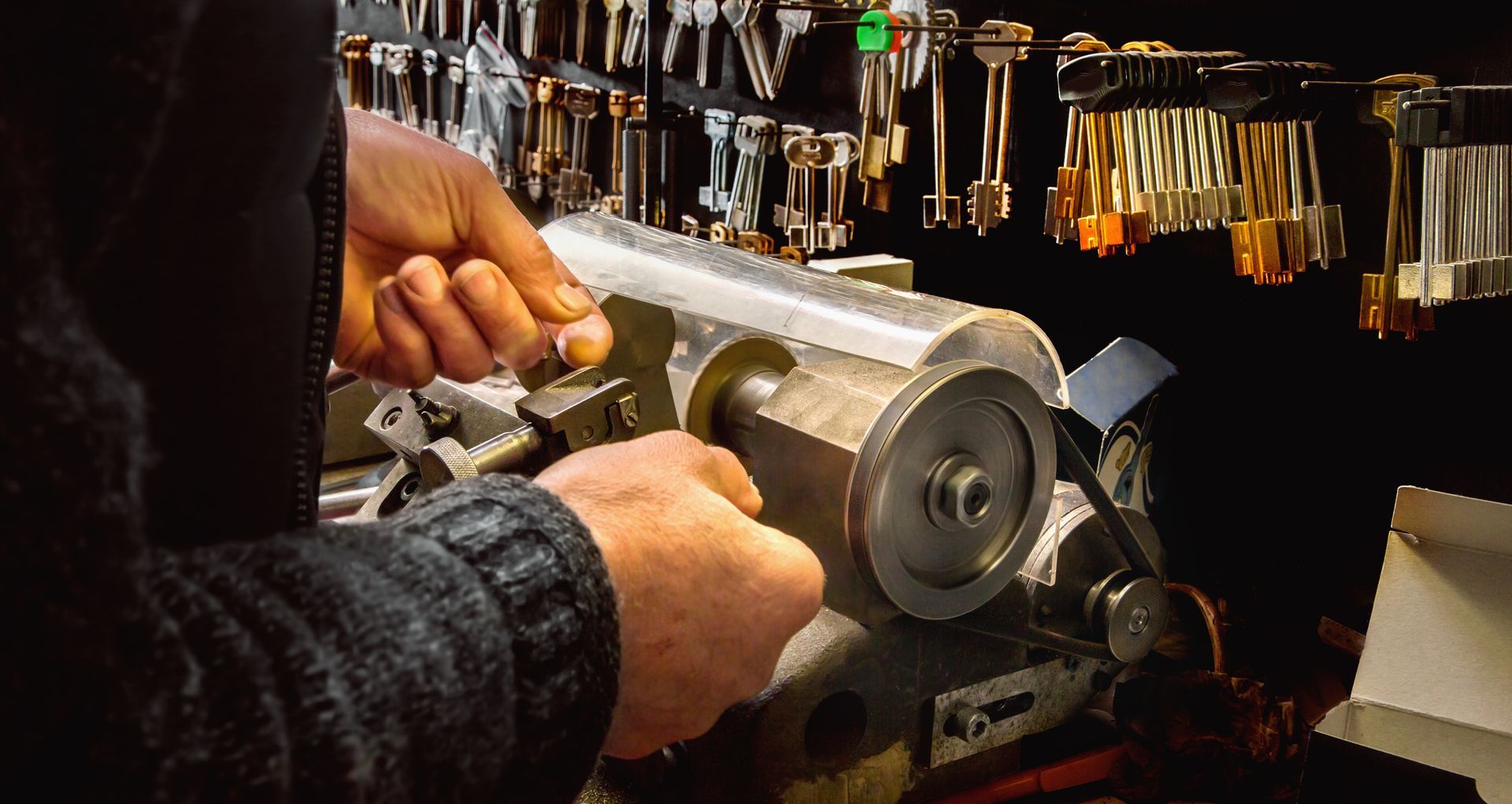 Person using a key-cutting machine in front of a wall of keys.