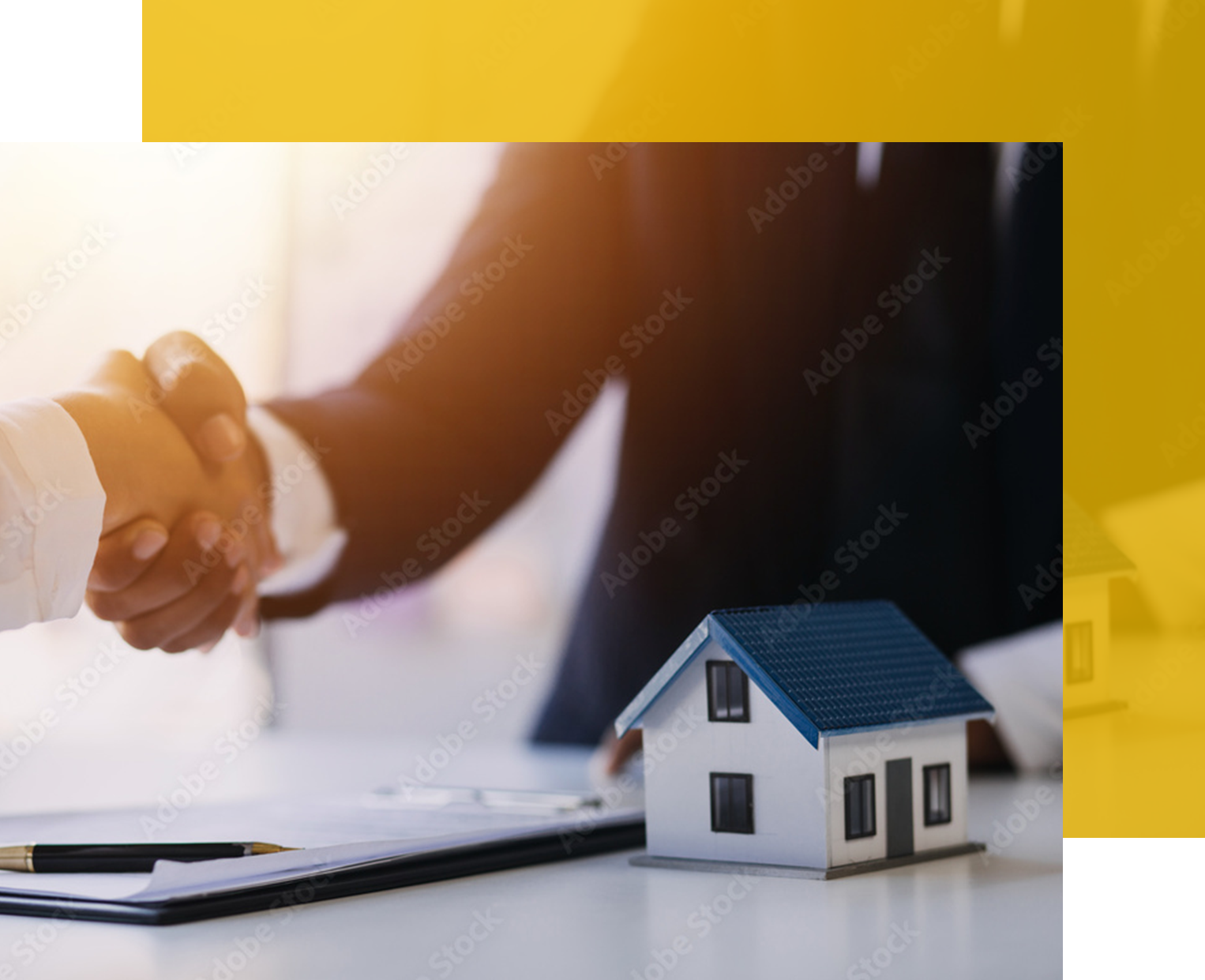 People shaking hands over a miniature house and documents, symbolizing a real estate deal.