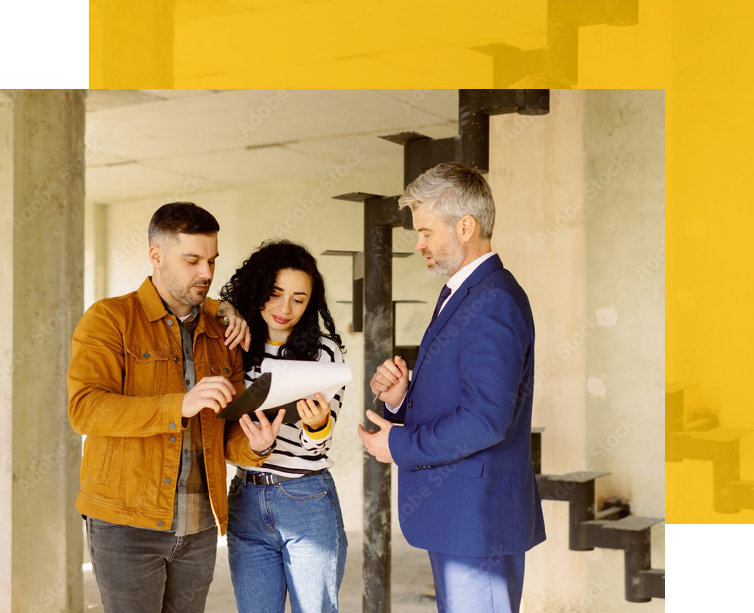Couple reviewing documents with a man in a suit, possibly discussing construction or real estate inside a building.