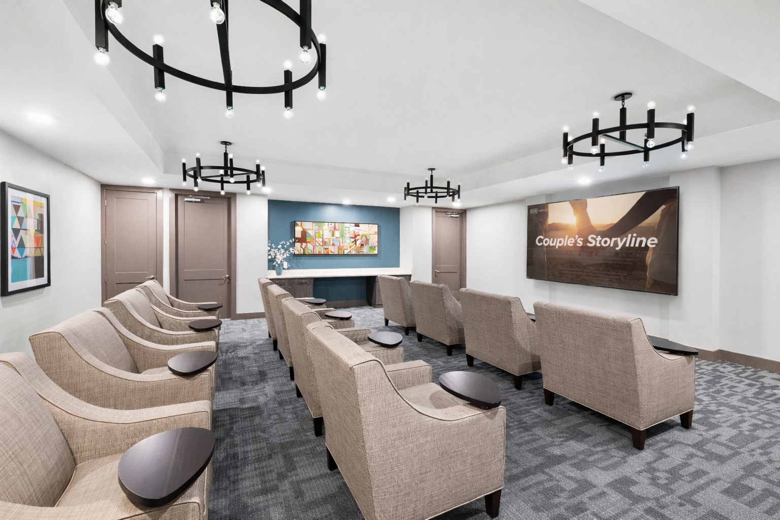 Modern waiting room with beige chairs, black ceiling lights, and wall art in a bright office lounge