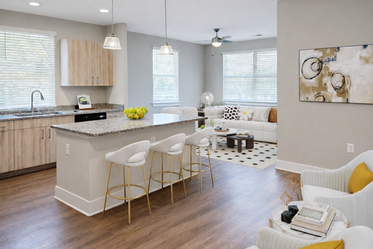 Open-concept kitchen and living area with granite island, bar stools, and white seating.