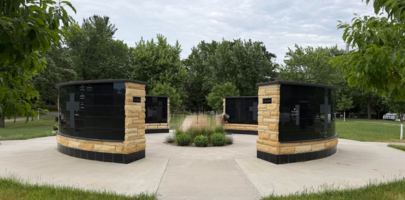 Brick grills in a park with a concrete path and trees surrounding them
