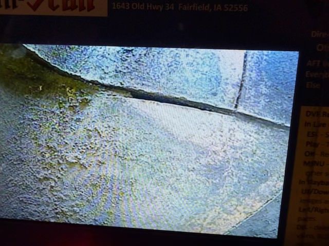 Close-up of rough concrete pavement beside a curb, with a blue-gray road edge.