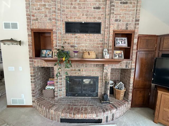Brick fireplace with mantel, brick hearth, and built-in cabinets in a living room