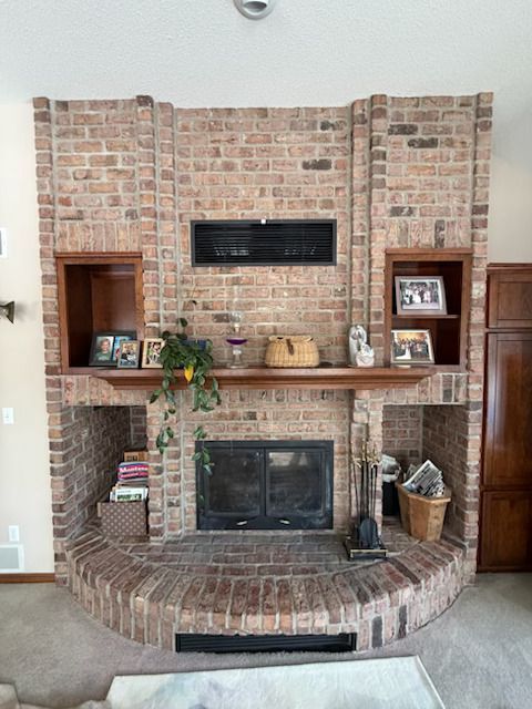Brick fireplace with built-in shelves, a black insert, and holiday decorations in a living room.