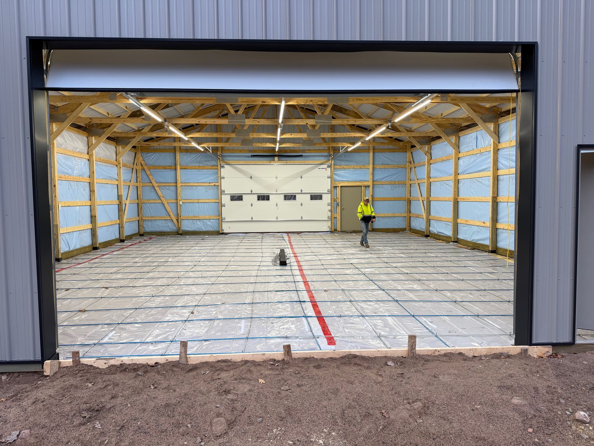 Large garage under construction with exposed wood framing and a worker near the back wall