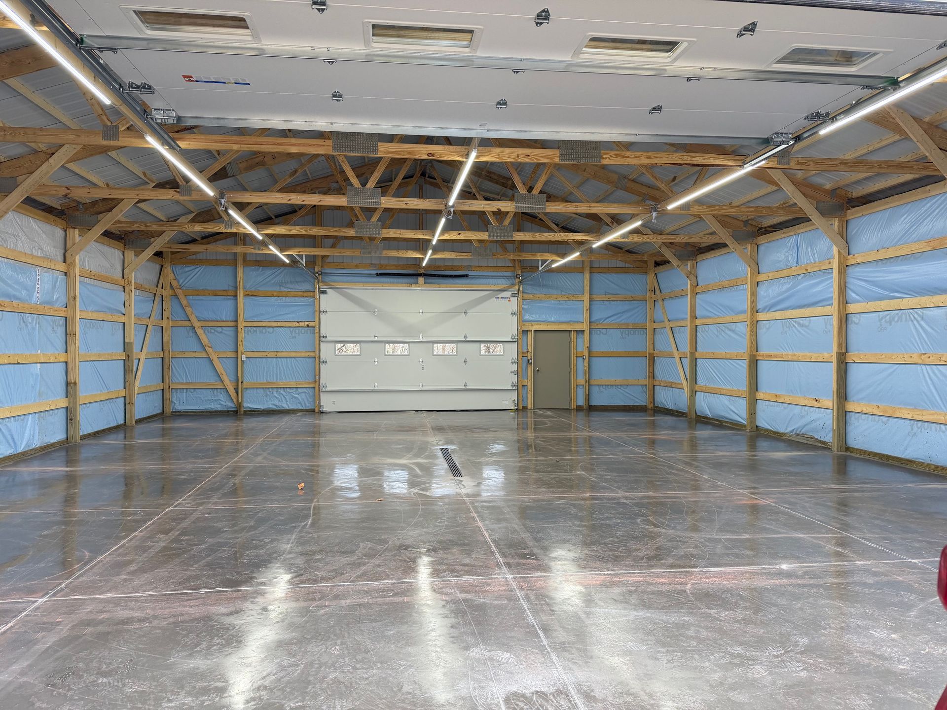 Empty garage with exposed wooden framing, insulated walls, and a concrete floor