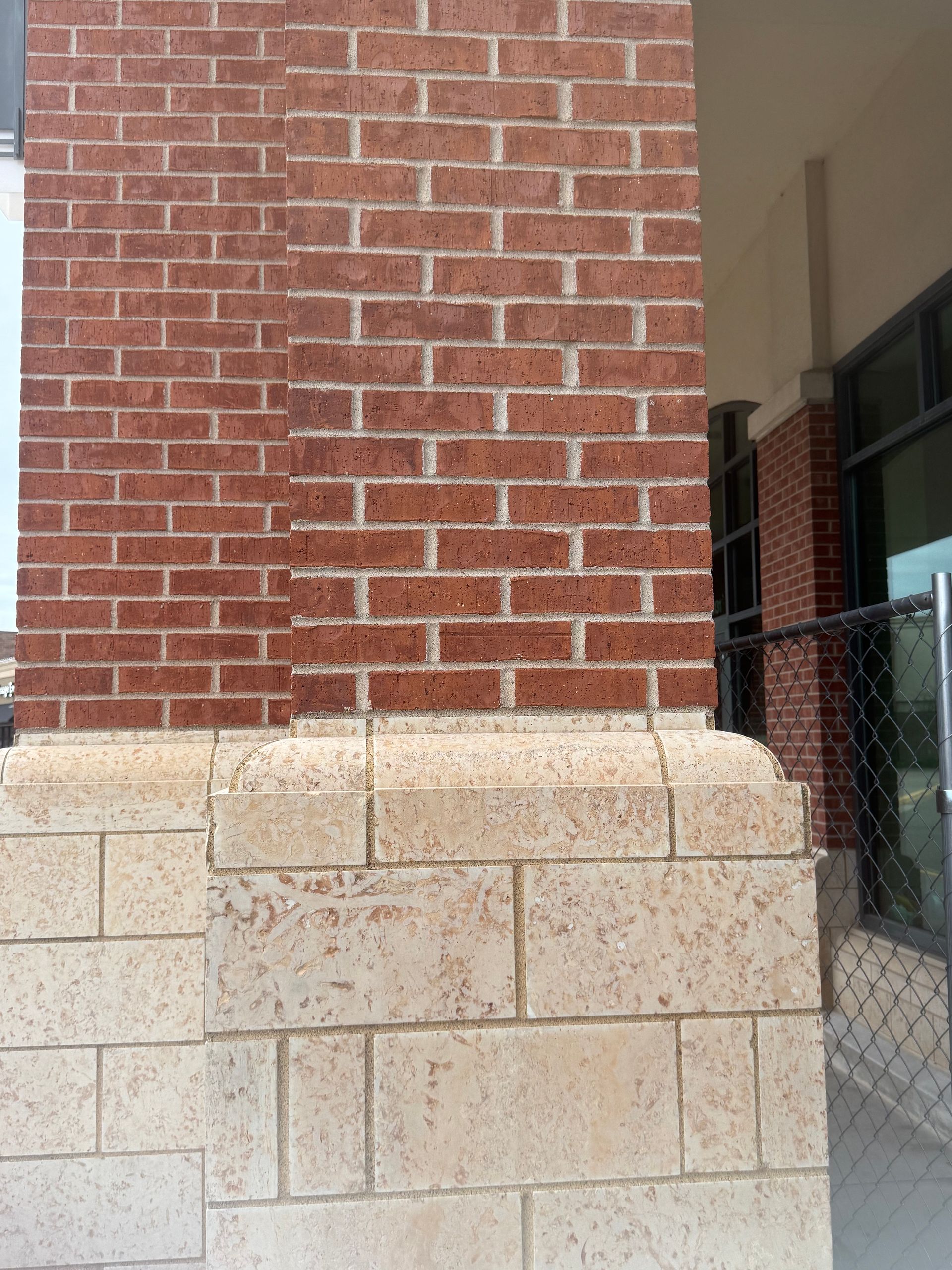 Brick building exterior with beige stone base and covered walkway entrance