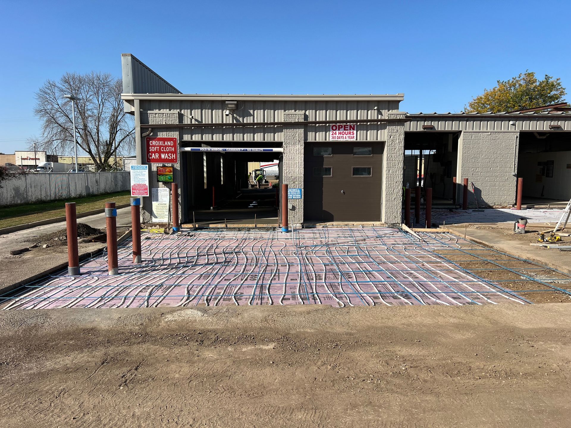 Construction site with a small building, brick-paved foreground, and open doorways under a clear sky