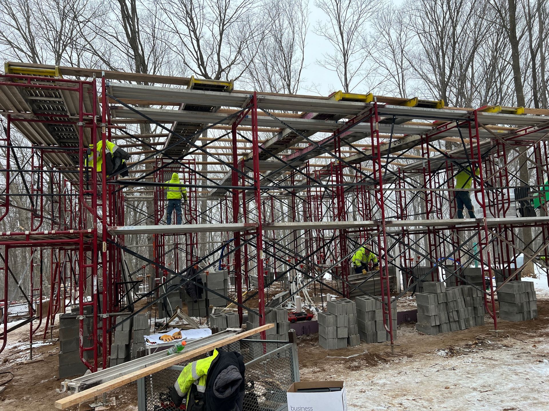 Construction site with red scaffolding and workers near a partially built concrete structure