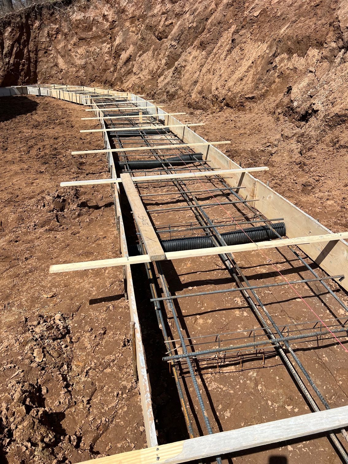 Rebar and wooden formwork in a dirt trench for a concrete foundation under construction