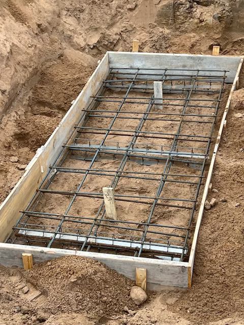 Concrete foundation formwork with steel rebar grid in an excavated dirt trench