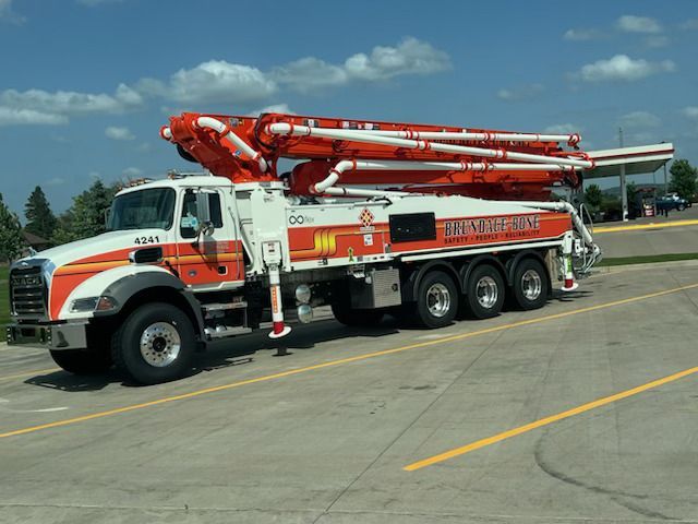 Red and white ladder fire truck parked on a paved lot under a blue sky.