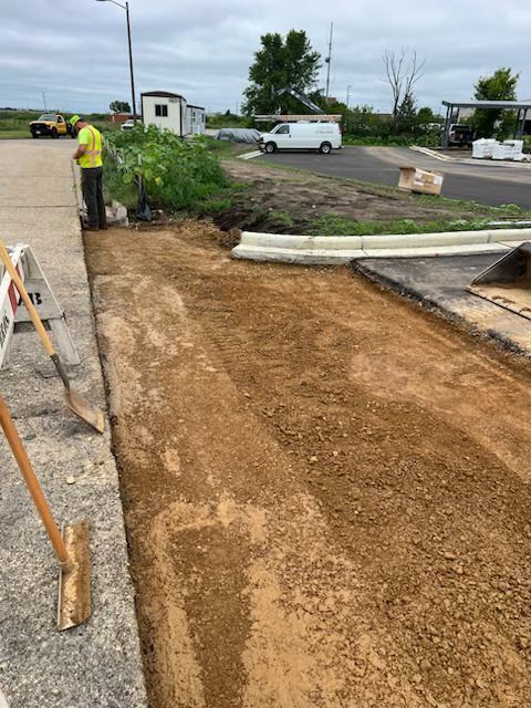 Construction worker marking a dirt path beside a paved road with a white van nearby