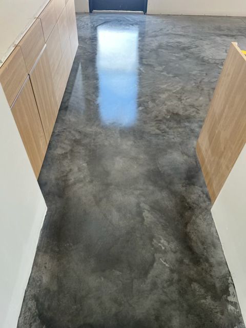 Polished concrete hallway with light wood cabinets and a bright window reflection on the floor