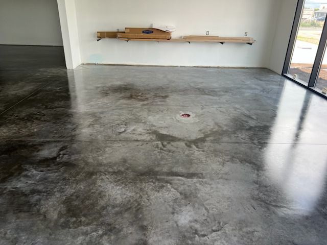 Empty room with polished concrete floor, wall shelf, and glass door letting in daylight