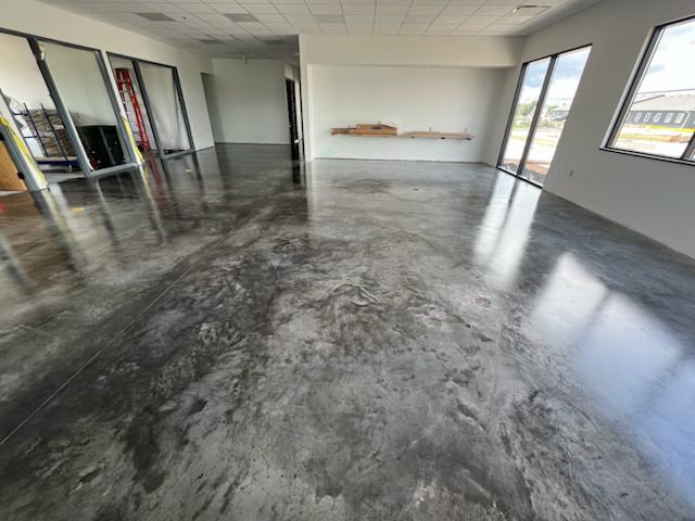 Empty commercial office with polished concrete floor and large windows.