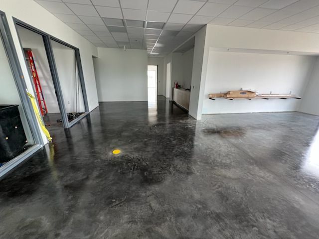Empty commercial office with glossy dark floor, white walls, and open doorways.