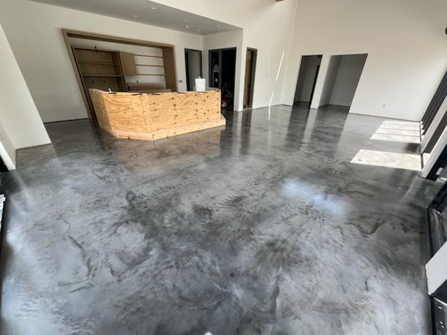 Empty modern room with glossy gray concrete floor and a wooden reception counter.