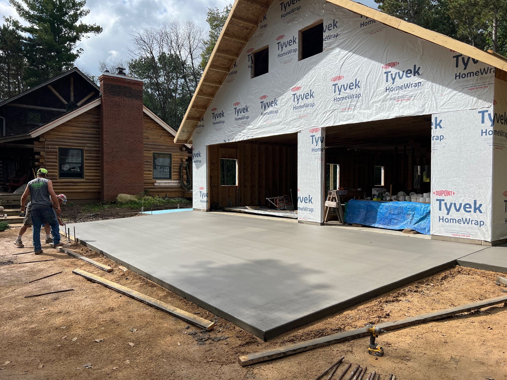 New house under construction with a concrete driveway and worker near the front entrance