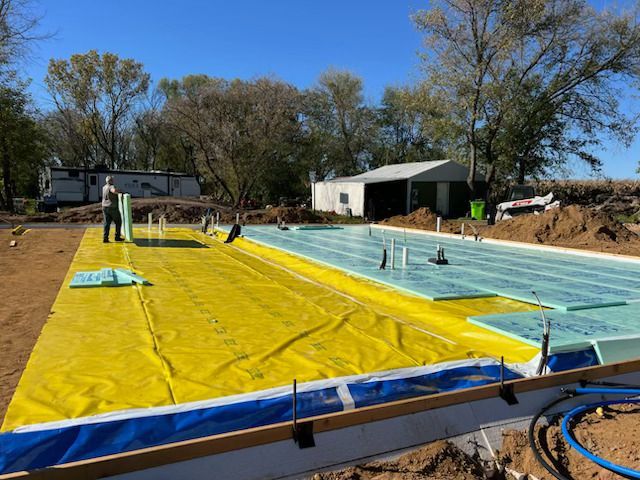 Pool under construction with blue liner, yellow cover, and workers on a sunny day
