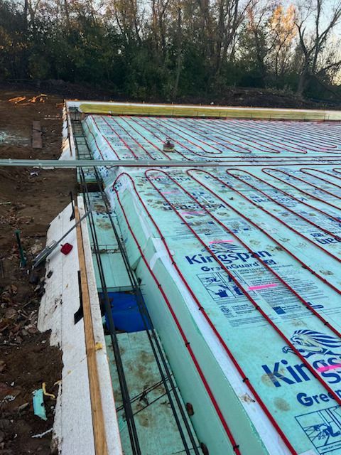 Foam-insulated roof under construction with a worker in the distance and trees behind