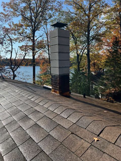 Lakefront rooftop with a tall chimney and autumn trees by the water