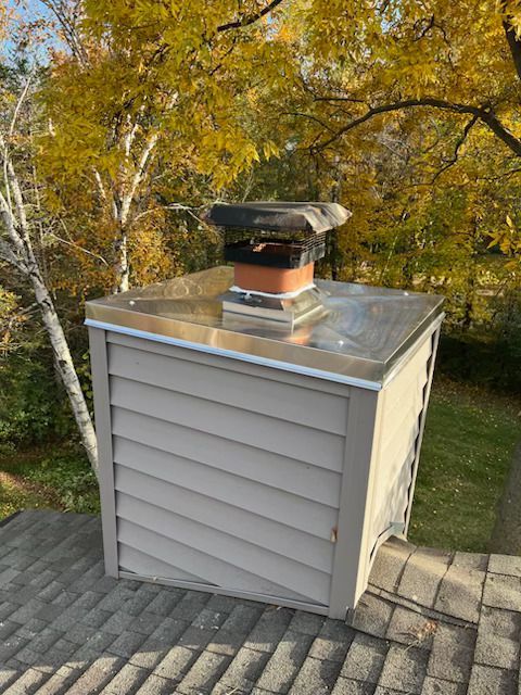 Beige rooftop vent on a small shed with a metal top, surrounded by autumn trees and grass.