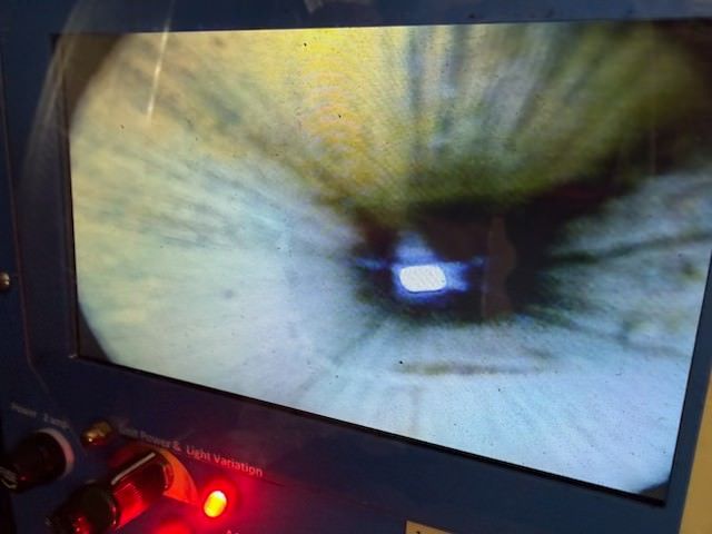Close-up of an eye on a screen with a red indicator light below it