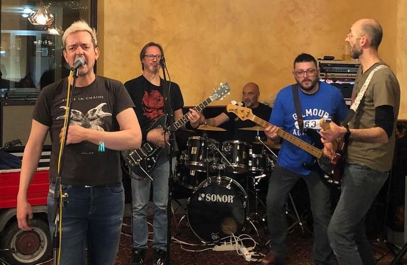Un gruppo di uomini suona la chitarra e canta nei microfoni.