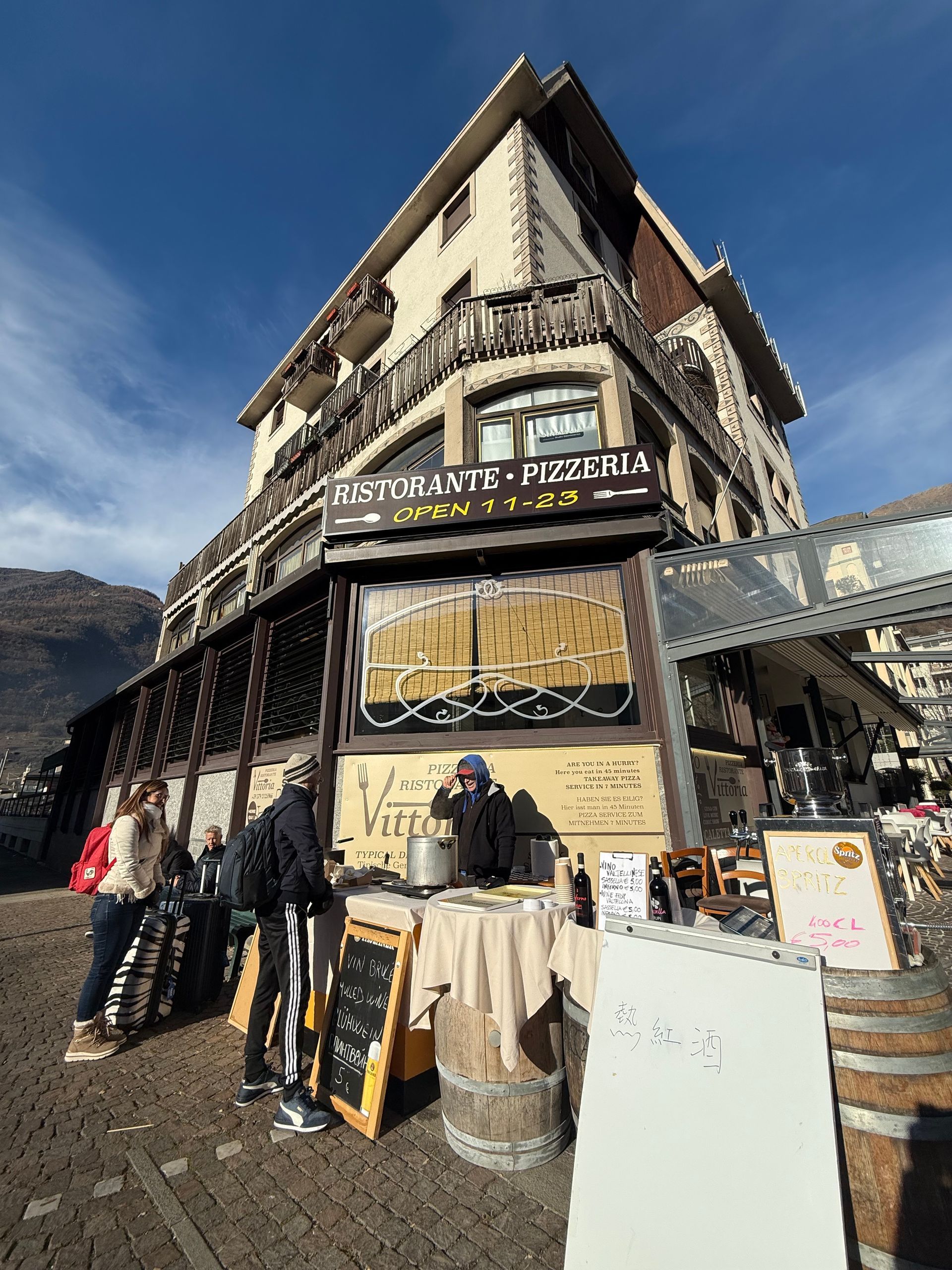 Un gruppo di persone è in piedi fuori da un ristorante.