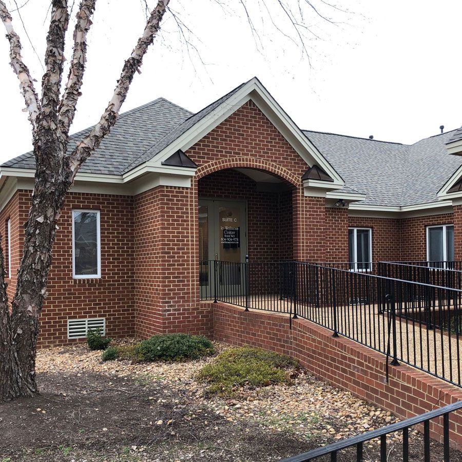 A brick building with a handicap ramp and a tree in front of it