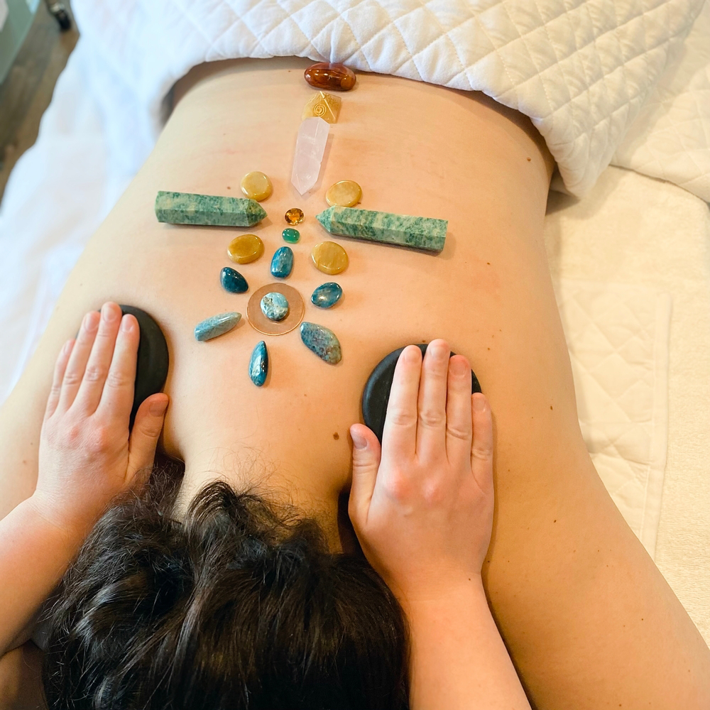 Person receiving a back massage with crystals arranged along the spine on a spa table