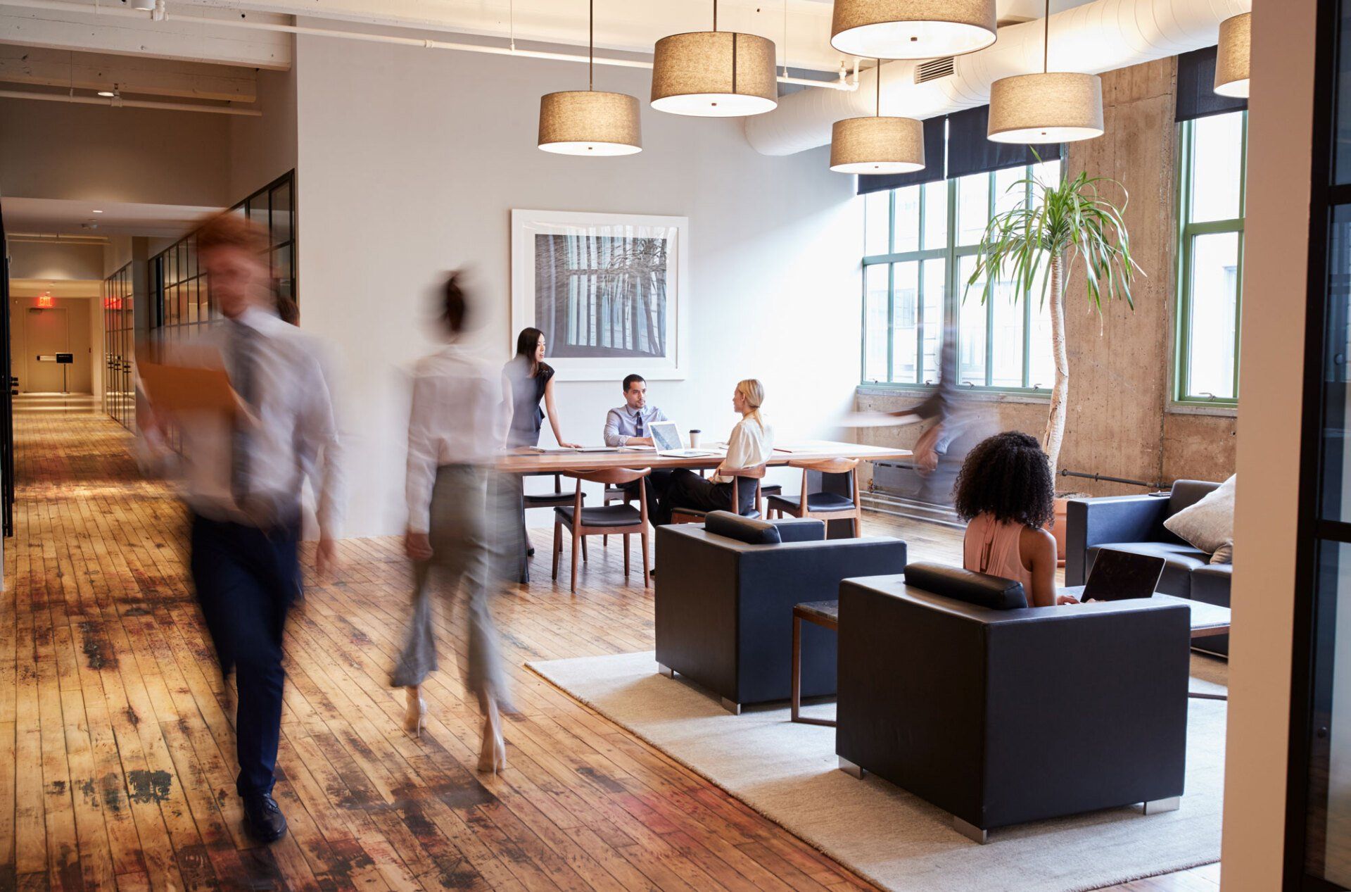 A group of people are walking through a living room in an office building.
