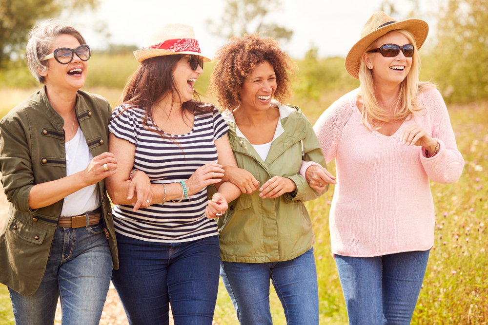 A group of women are walking in a field and laughing.