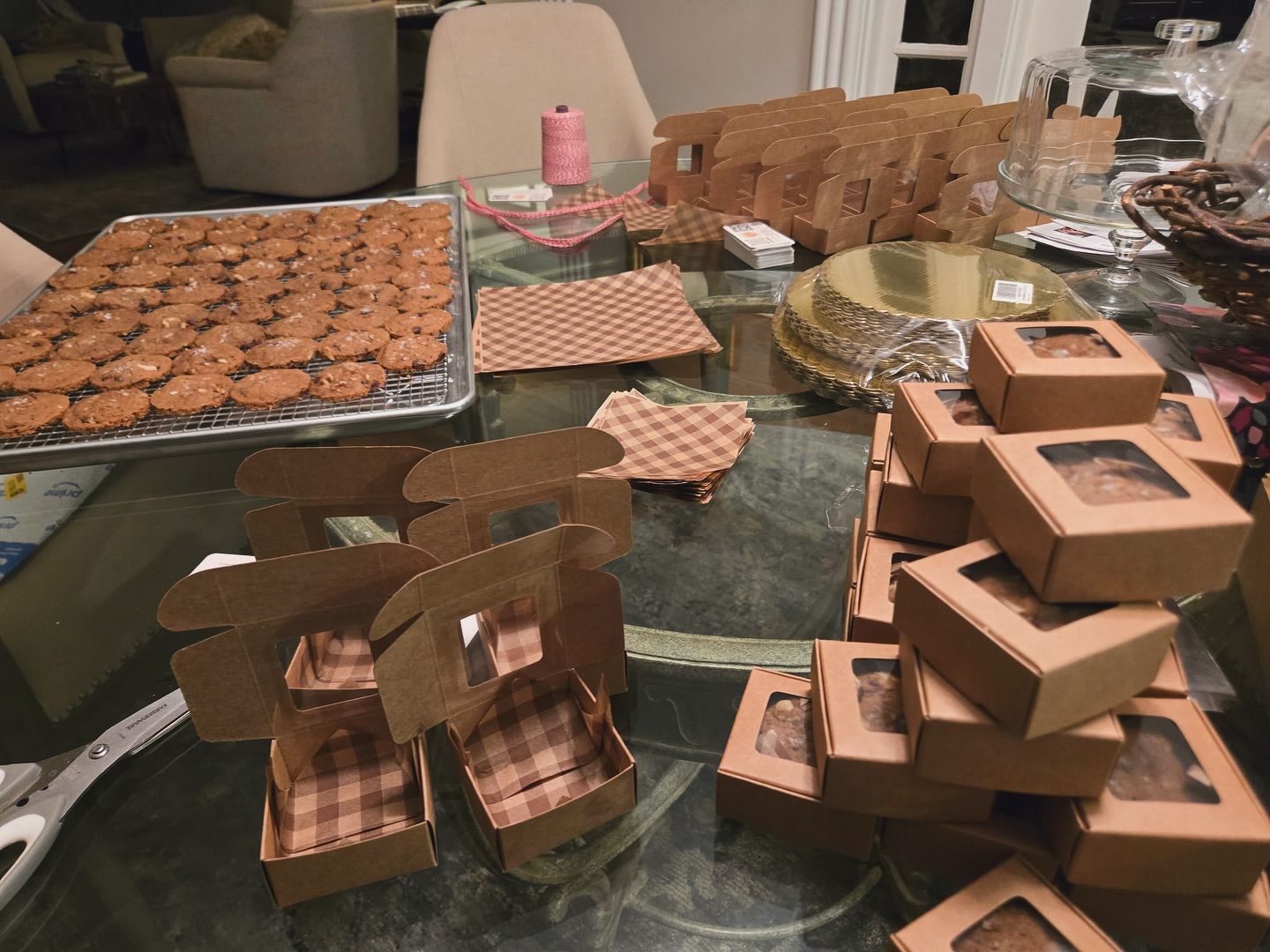Table covered with assorted brown cardboard boxes, trays, and baked goods on a kitchen counter