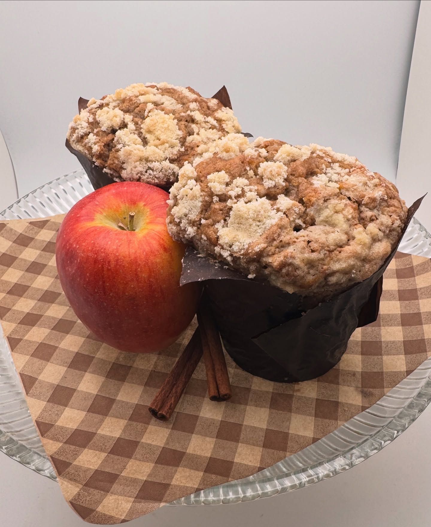 Apple and two crumb-topped muffins on a checkered plate