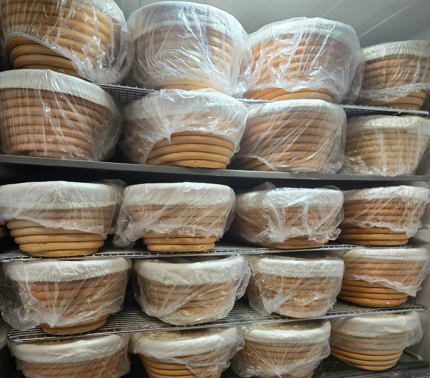 Stacked clear plastic tubs filled with tan folded items on store shelves