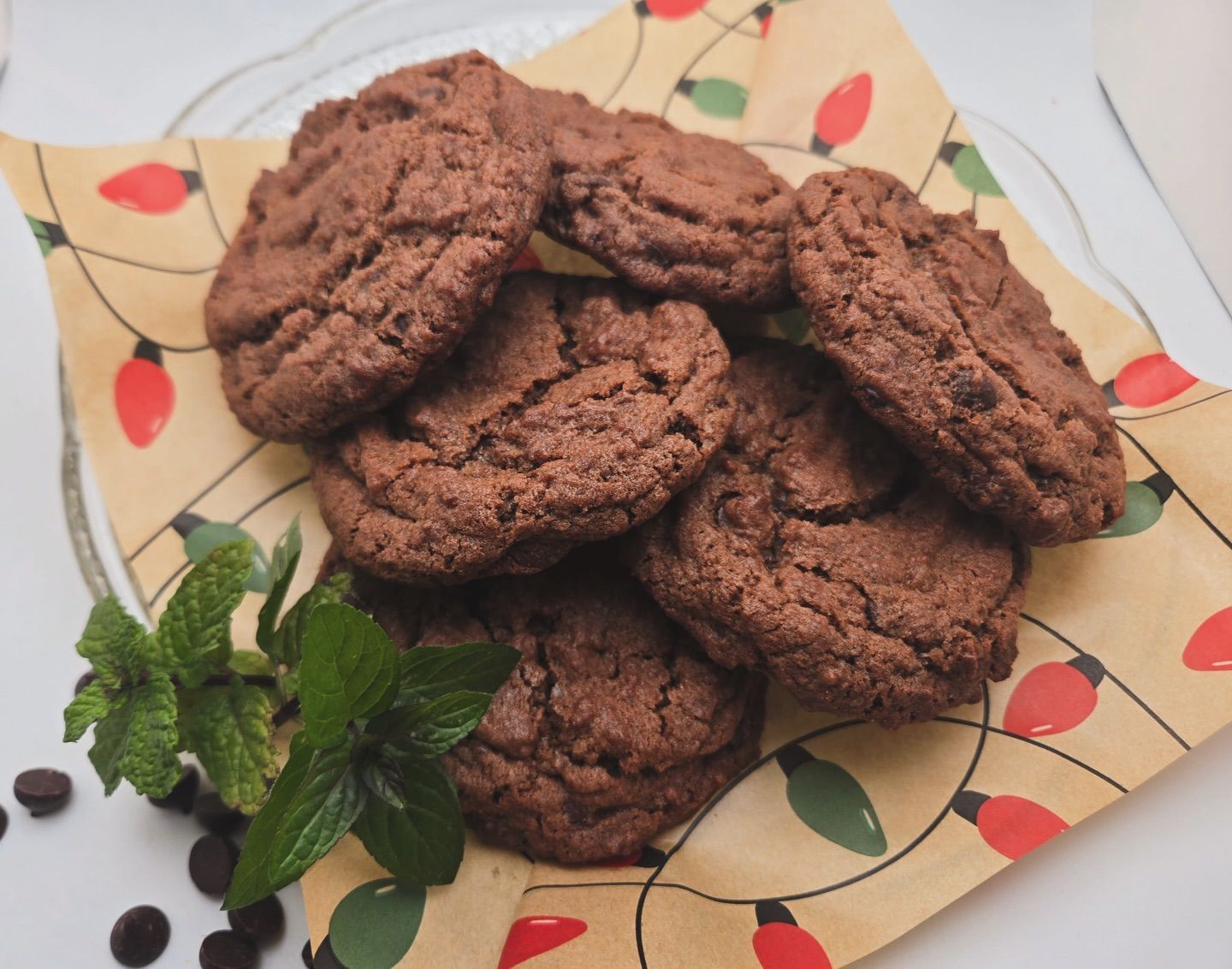 Stack of chocolate cookies on a decorative napkin with mint leaves and chocolate chips