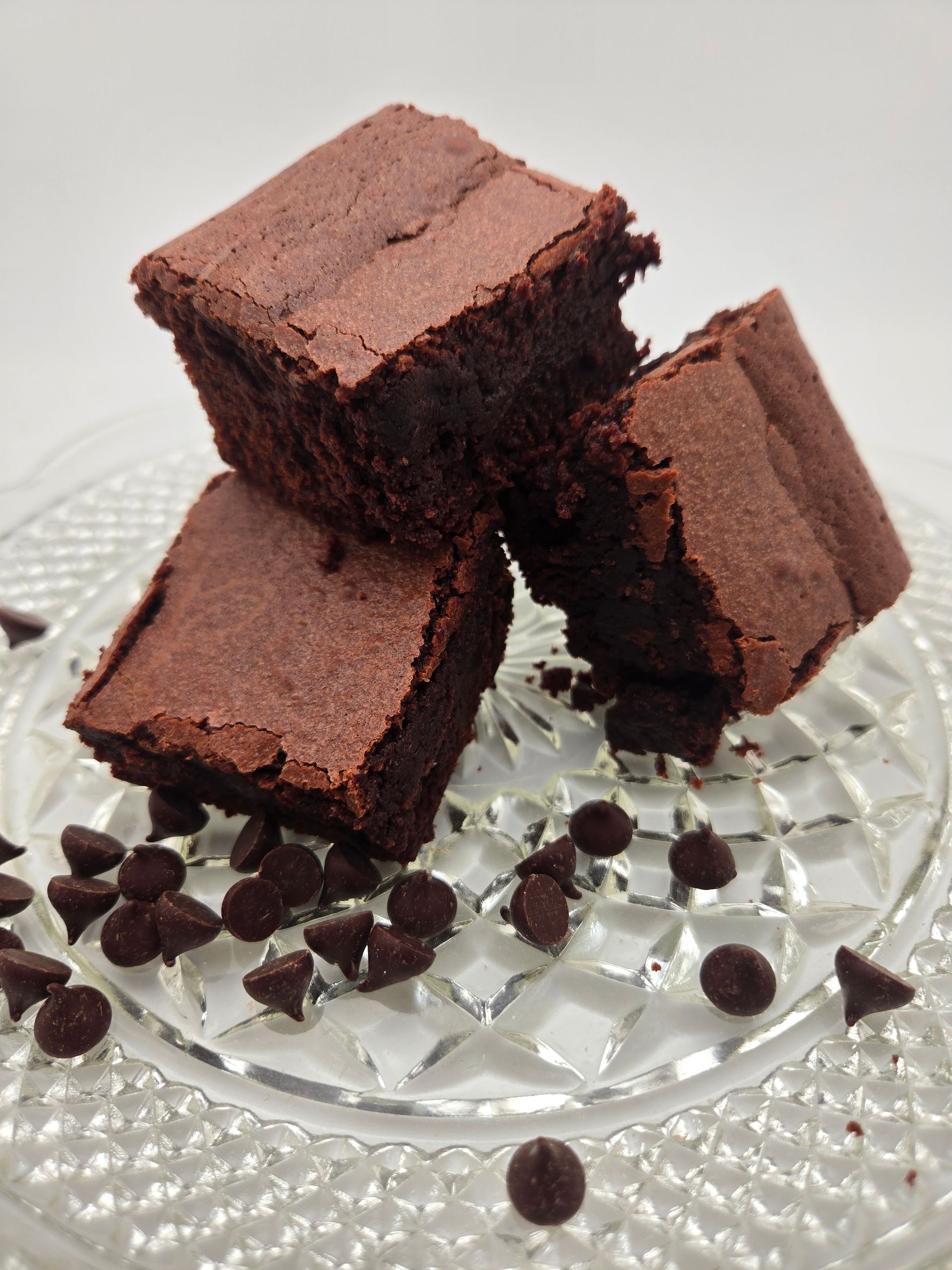 Close-up of heart-shaped cookies with white icing and red sprinkles on a glass tray