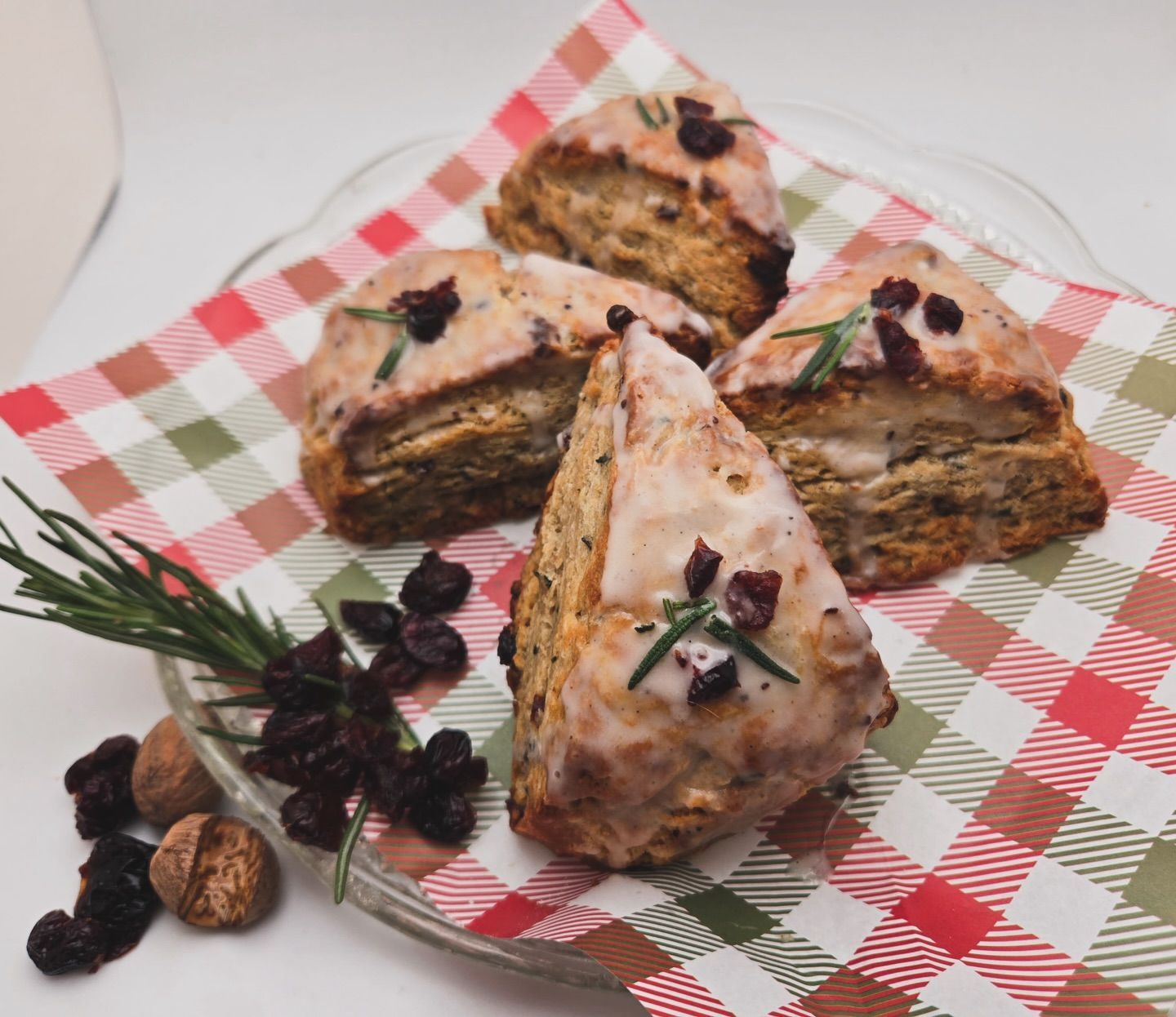 Triangular layered pastry slices with pink icing and berries on a red-and-white checkered cloth