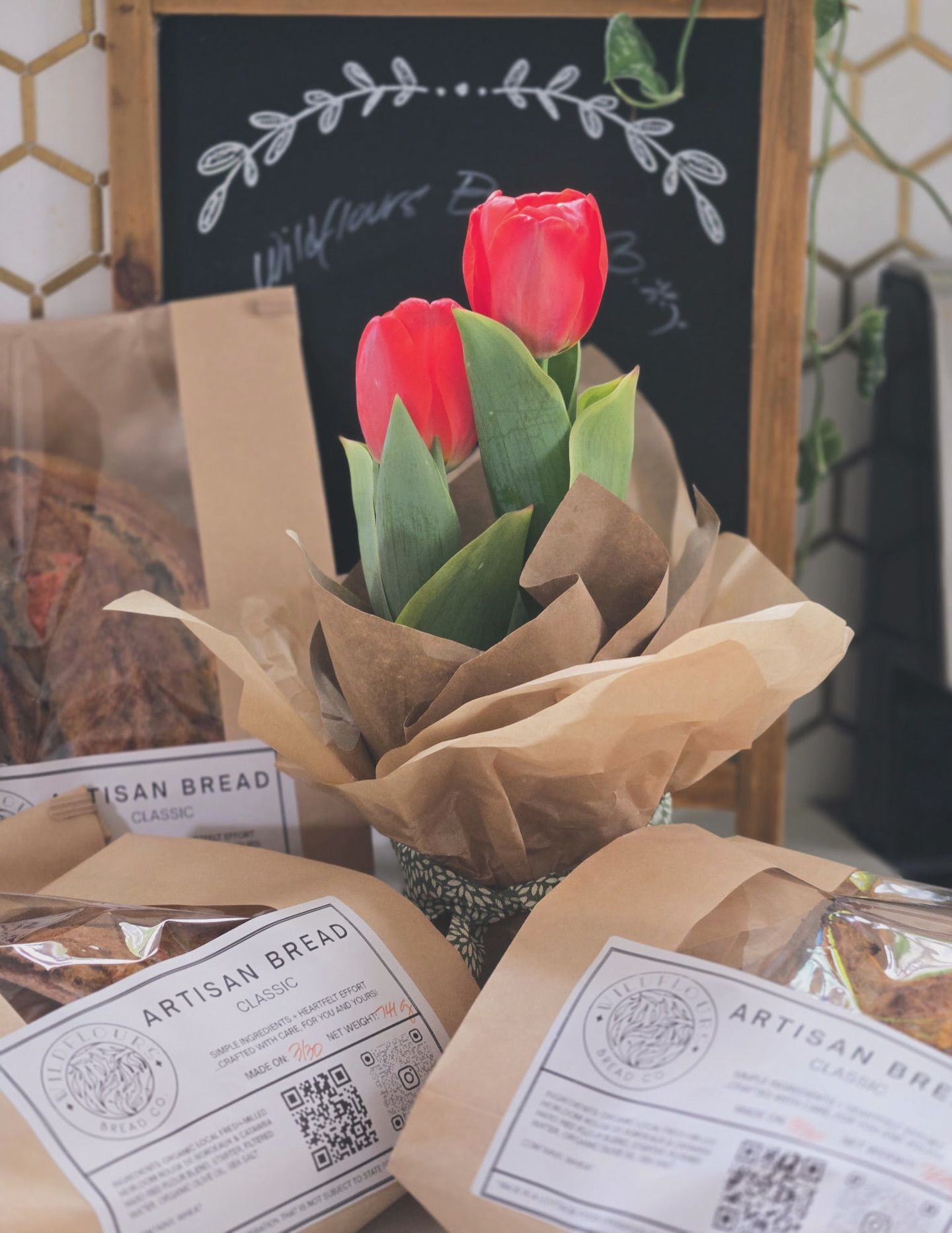 Wrapped red tulips with artisan bread packages in a bakery display