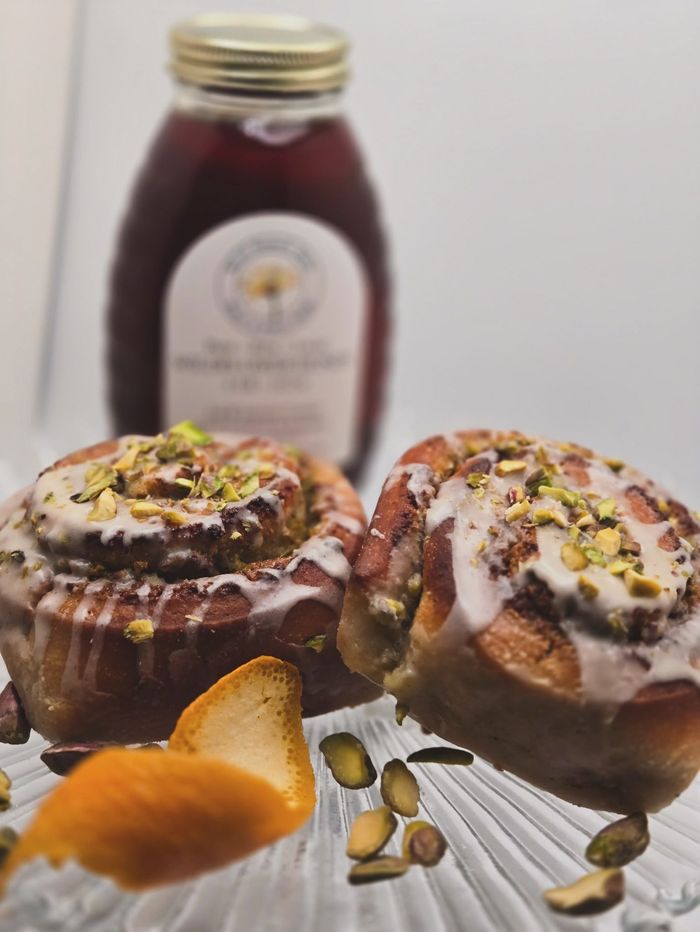 Chocolate-drizzled pistachio pastries with honey and a honey jar in the background