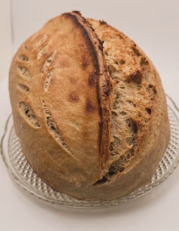 Round loaf of rustic bread on a clear glass plate