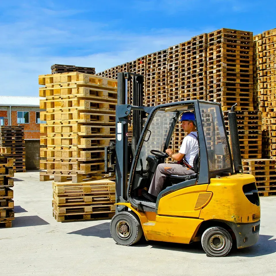 Man Driving Forklift With Wood Pallets