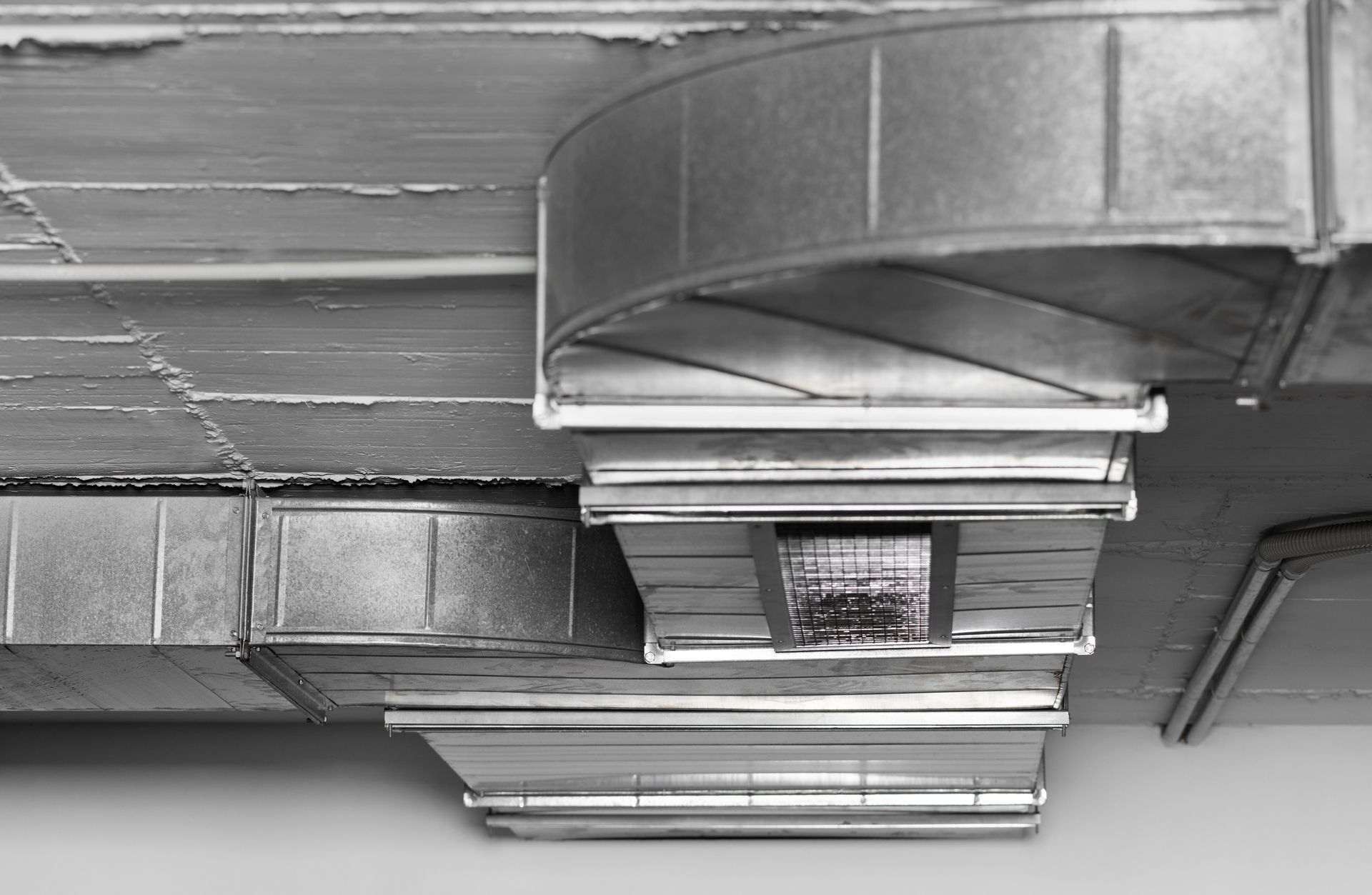 Underside of a metal HVAC duct and ceiling vents in a building interior