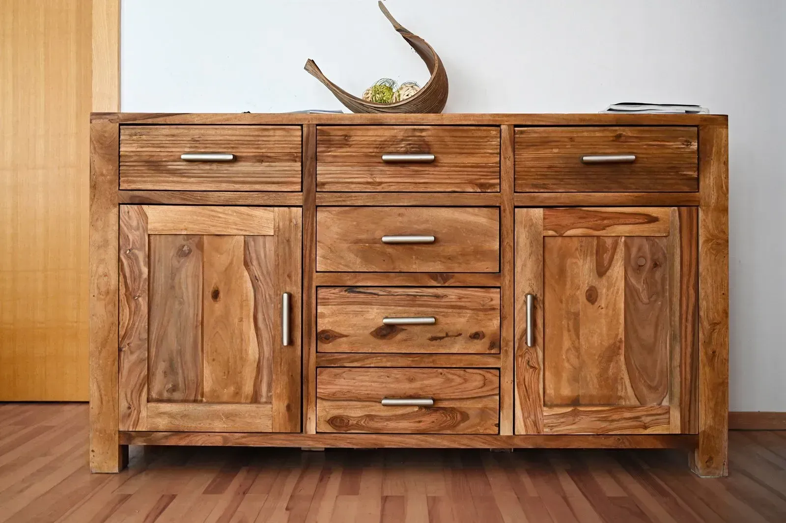 Wooden cabinet with drawers and doors; a decorative item on top.
